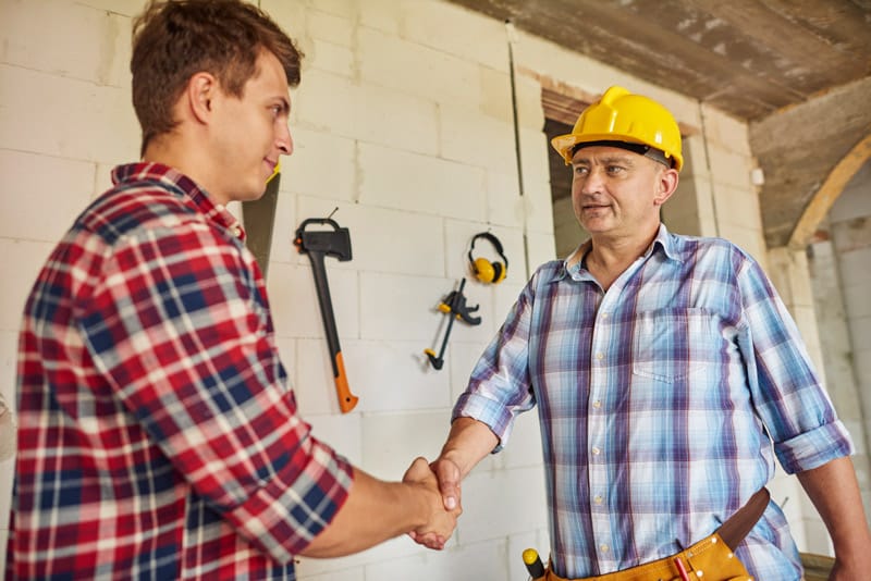 Poignée de main entre un entrepreneur du bâtiment et un particulier